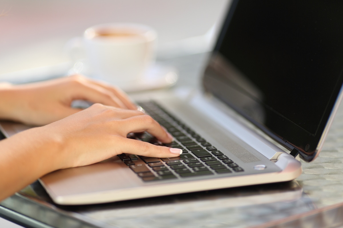 Close up of a woman hands working with a laptop in a coffee shop table