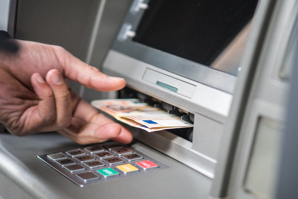 Man collecting cash from cashpoint.