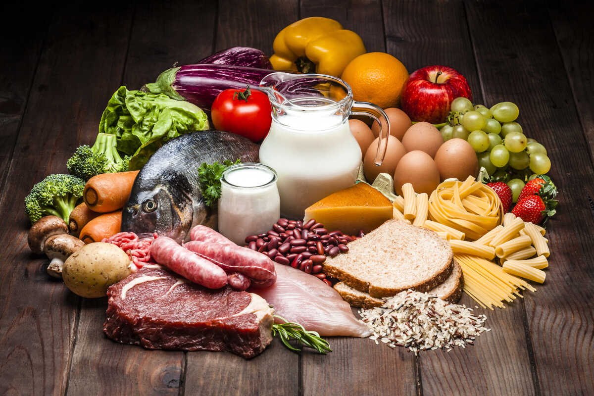Large group of different types of food like carbohydrates, protein and dietary fiber shot on rustic wooden table. Food included in the composition are dairy products, sausages, minced meat, fish, bread, pasta, beans, fruits and vegetables. DSRL studio photo taken with Canon EOS 5D Mk II and Canon EF 70-200mm f
