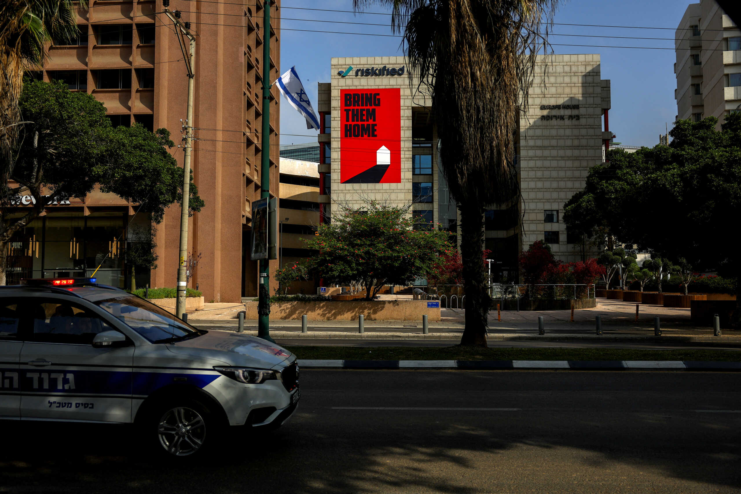 An Israeli police car drives past a billboard in support of hostages kidnapped in the deadly October 7 attack on Israel by the Palestinian Islamist group Hamas from Gaza, amid the ongoing conflict between Israel and the Palestinian Islamist group Hamas, in Tel Aviv, Israel March 30, 2024. REUTERS