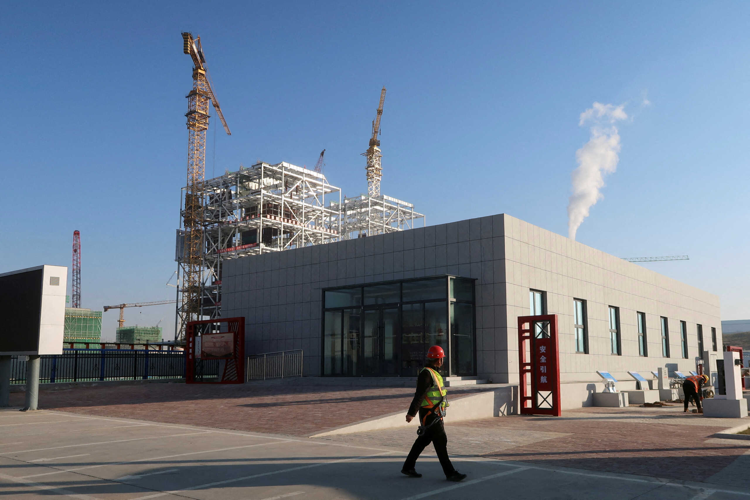 FILE PHOTO: A worker walks past cranes at Yushen Yuheng power plant, a coal-fired power plant under construction, in Yulin, Shaanxi province, China November 21, 2023. REUTERS