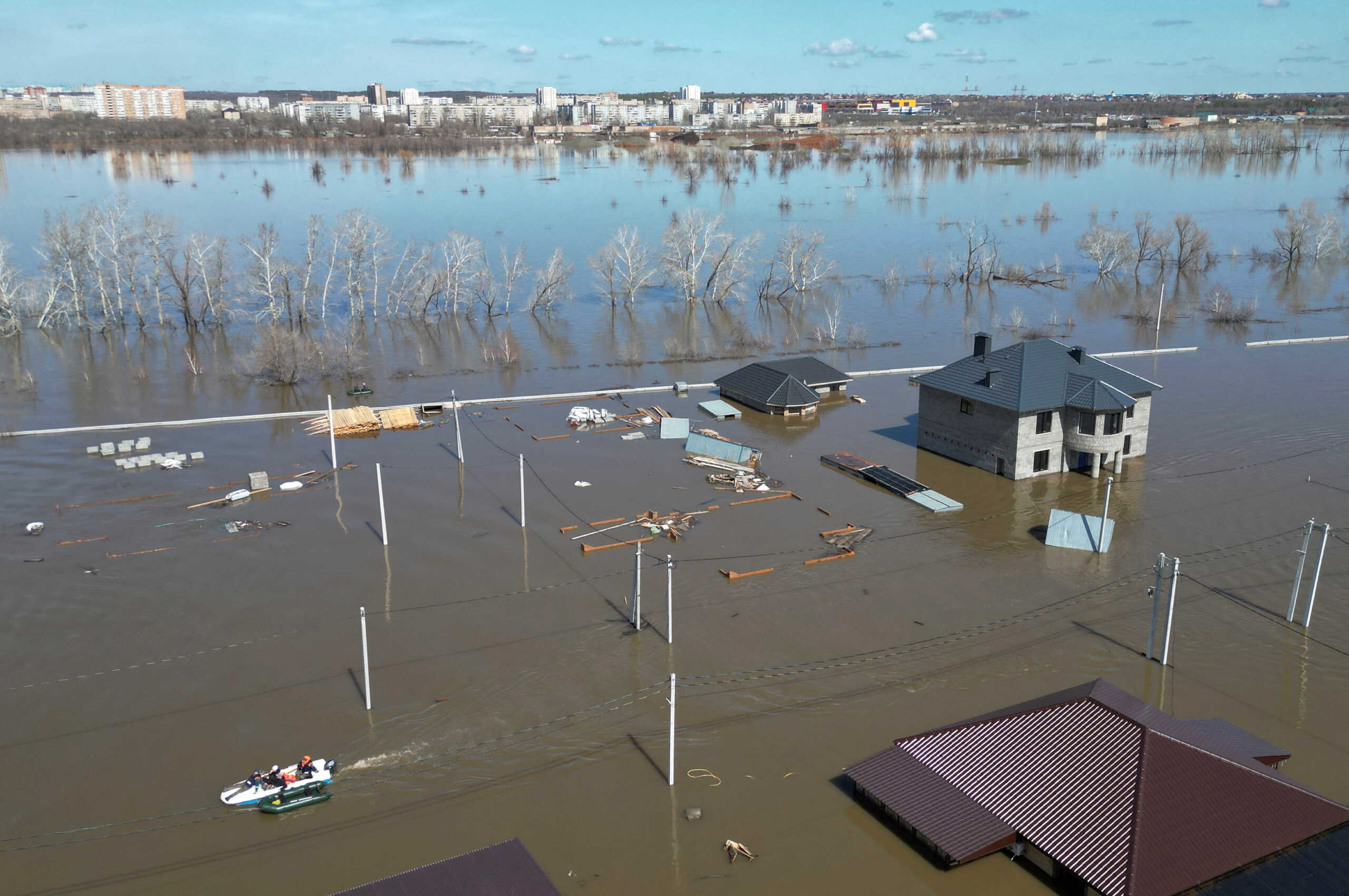 People ride a boat in the flooded residential area in Orenburg, Russia, April 11, 2024. REUTERS