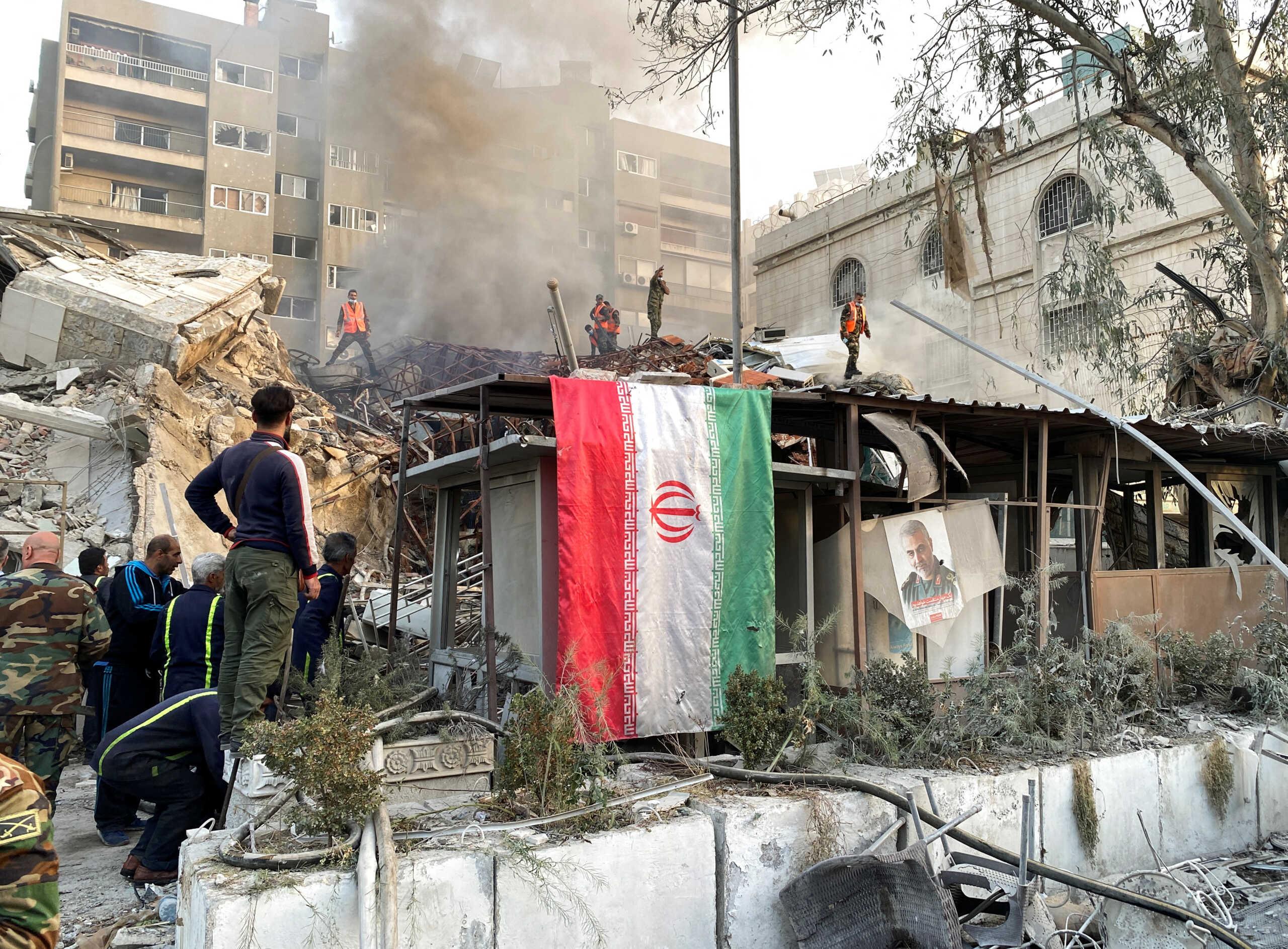 An Iranian flag hangs as smoke rises after what the Iranian media said was an Israeli strike on a building close to the Iranian embassy in Damascus, Syria April 1, 2024. REUTERS