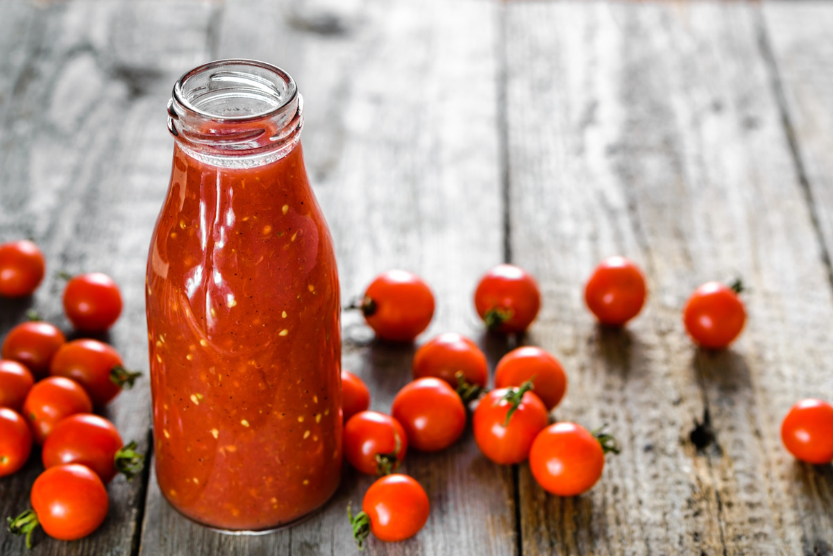 Bottle of tomato juice and fresh tomatoes on wooden background, organic healthy food concept