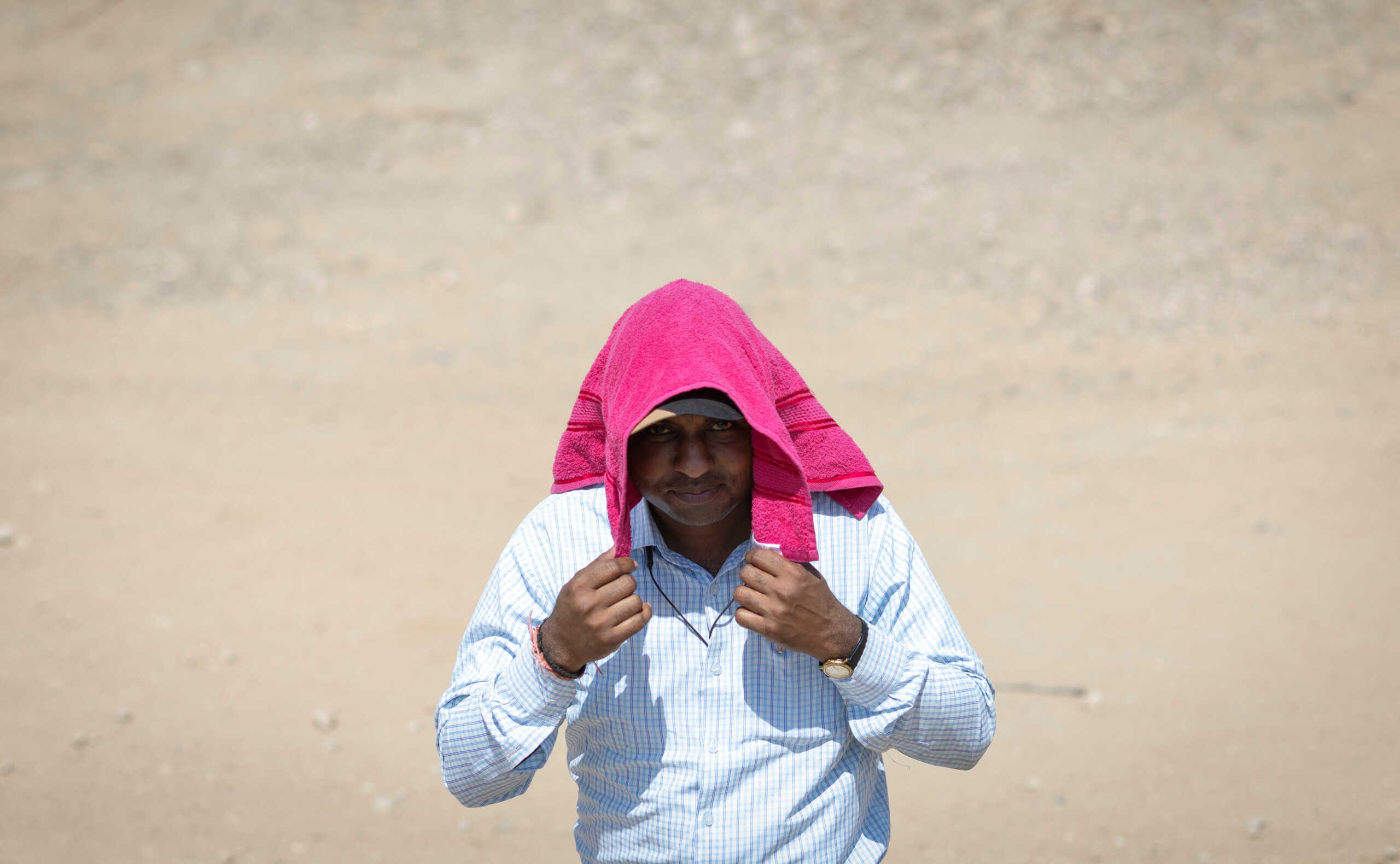 A polling officer covers himself with a towel, to protect from heat on a hot summer day, as he walks towards his designated vehicle after collecting election materials at a distribution centre, ahead of the second phase of the general elections, in Barmer in the desert state of Rajasthan, India, April 25, 2024. REUTERS