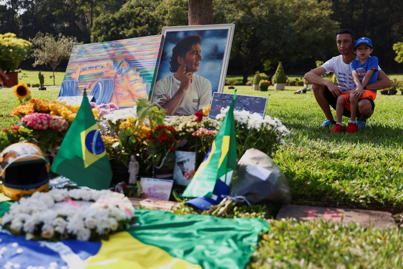 An Ayrton Senna fan and a boy look at the racing driver's grave, thirty years after his death, in Sao Paulo, Brazil May 1, 2024. REUTERS