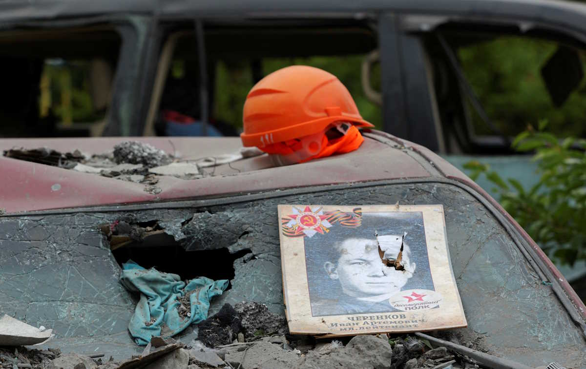 A placard prepared for the Immortal Regiment event annually observed in Russia on Victory Day, that marks the anniversary of the victory over Nazi Germany in World War Two, is placed on a destroyed car in the courtyard of a multi-story apartment block, a section of which collapsed as the result of what local authorities called a Ukrainian missile strike, in the course of Russia-Ukraine conflict in the city of Belgorod, Russia, May 13, 2024. REUTERS