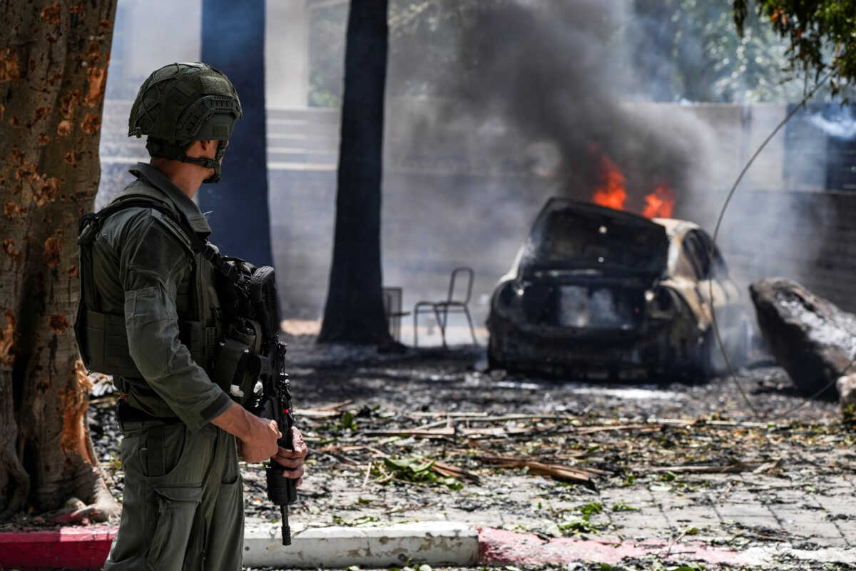 A soldier looks at a burning car at the impact site of a rocket that was fired towards Israel from Lebanon, amid ongoing cross-border hostilities between Hezbollah and Israeli forces, in Kiryat Shmona, northern Israel, May 5, 2024. REUTERS