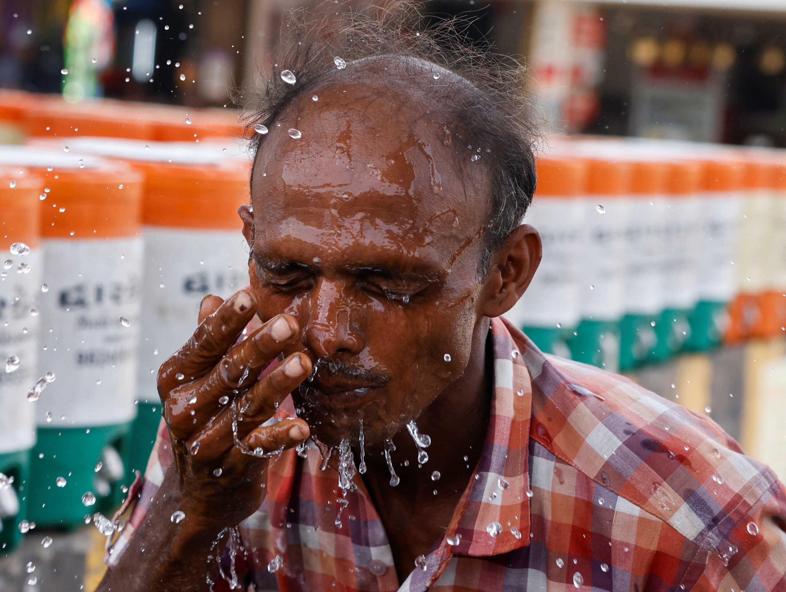 A man sprays cold water on his face from a water jar during a heatwave in Ahmedabad, India, May 29, 2024. REUTERS
