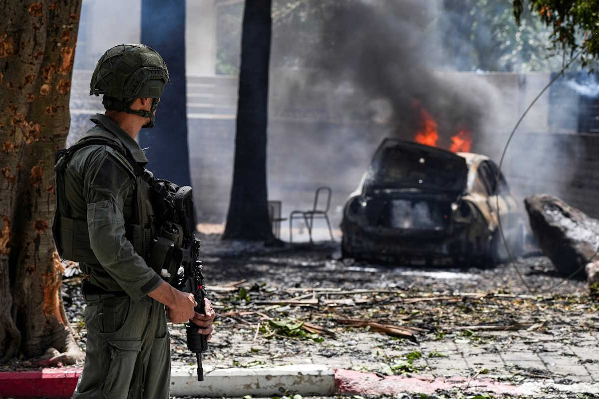 A soldier looks at a burning car at the impact site of a rocket that was fired towards Israel from Lebanon, amid ongoing cross-border hostilities between Hezbollah and Israeli forces, in Kiryat Shmona, northern Israel, May 5, 2024. REUTERS
