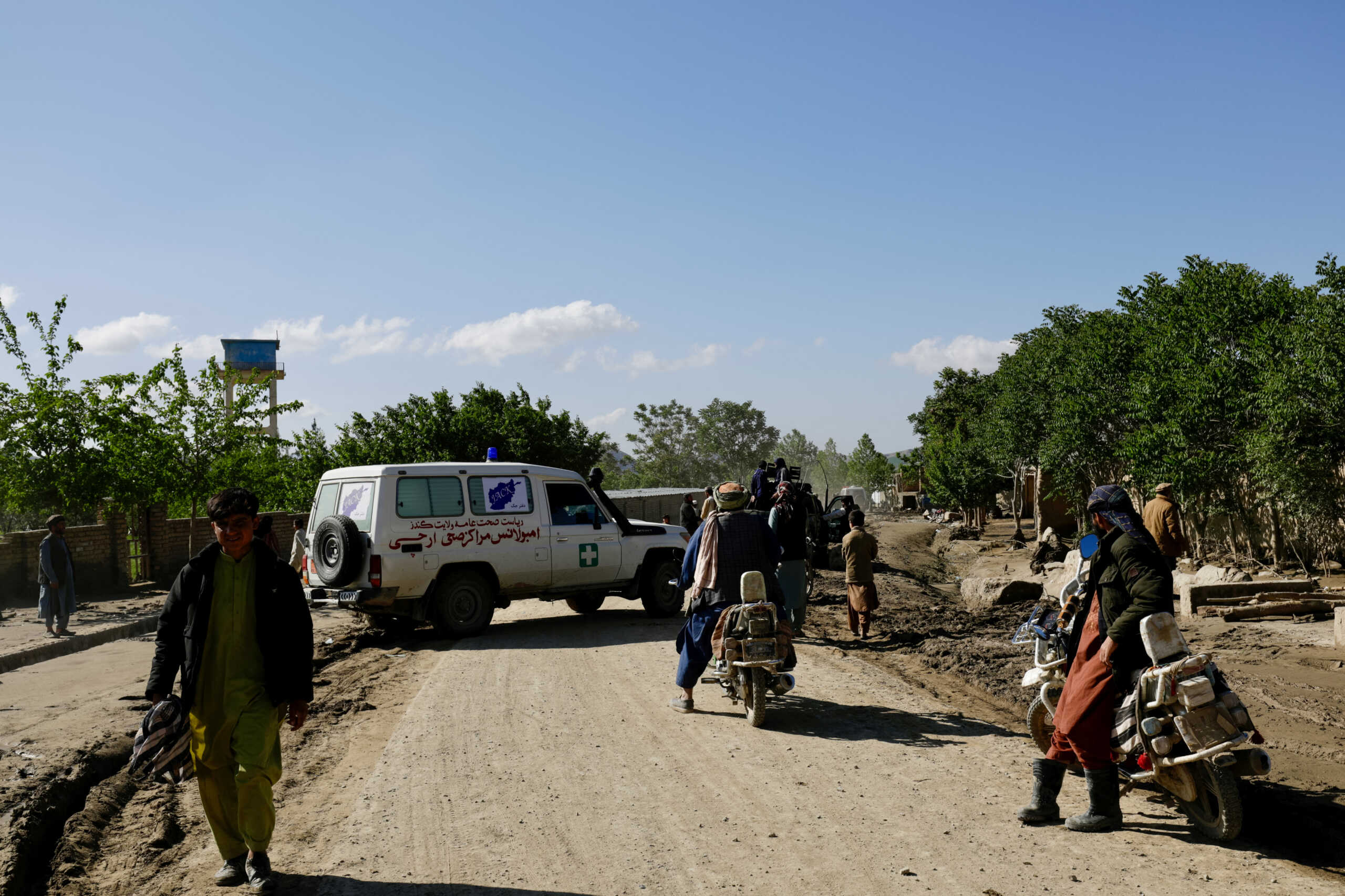 An ambulance moves on a road next to mud and debris following a flash flood, in Burka District, Baghlan, Afghanistan, May 12, 2024. REUTERS