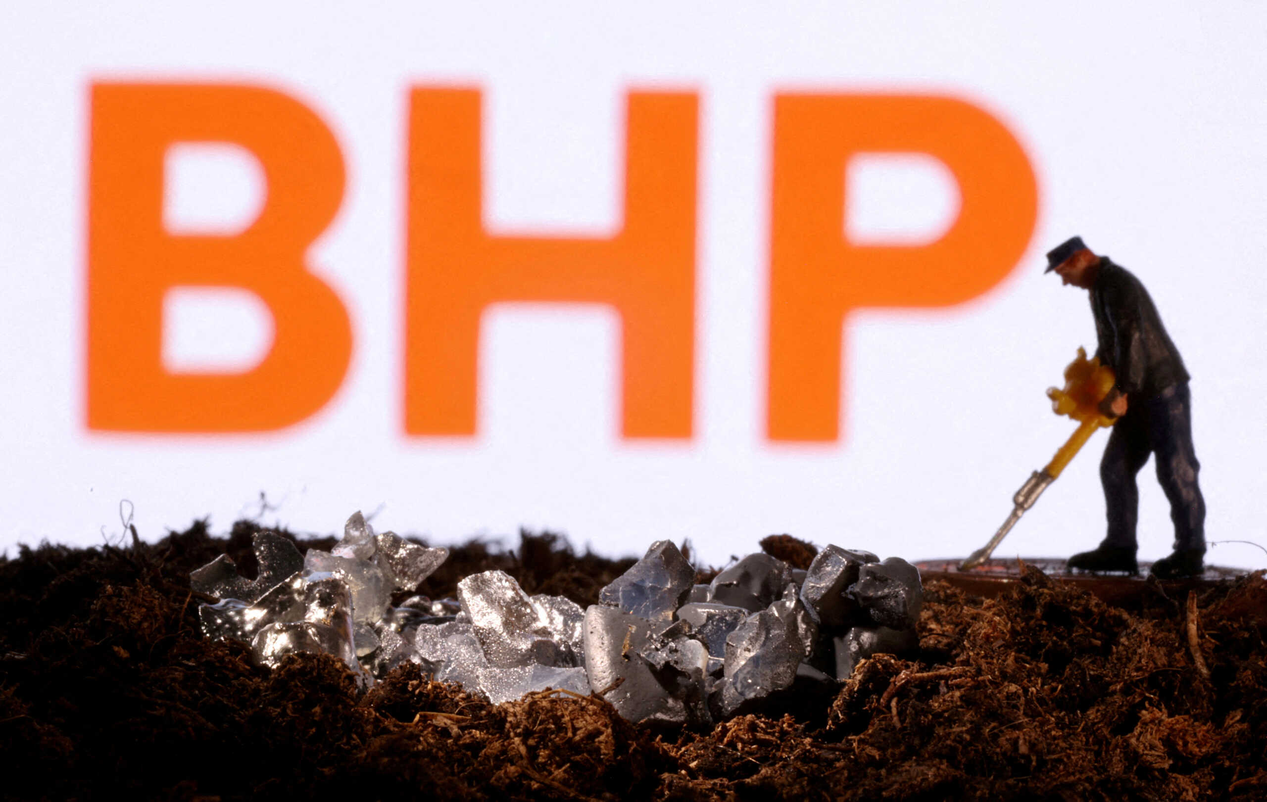 FILE PHOTO: A small toy figure and mineral imitation are seen in front of the BHP logo in this illustration taken November 19, 2021. REUTERS