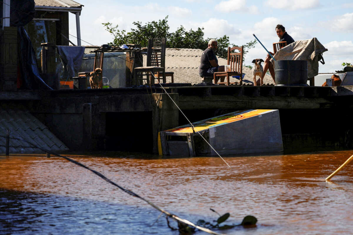 Men sit on a house's roof in an flooded area in Canoas, Rio Grande do Sul state, Brazil, May 14, 2024. REUTERS