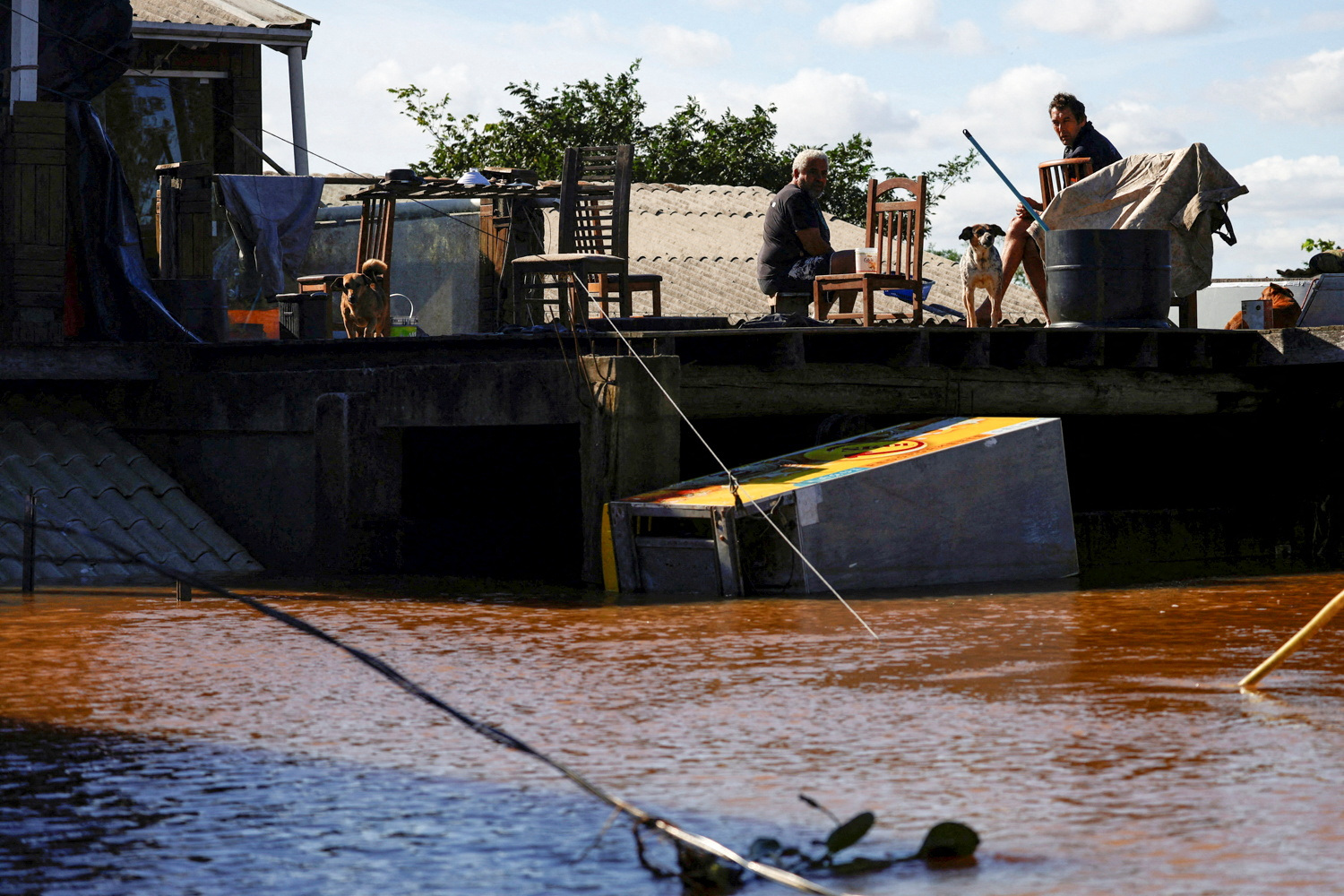 Men sit on a house's roof in an flooded area in Canoas, Rio Grande do Sul state, Brazil, May 14, 2024. REUTERS