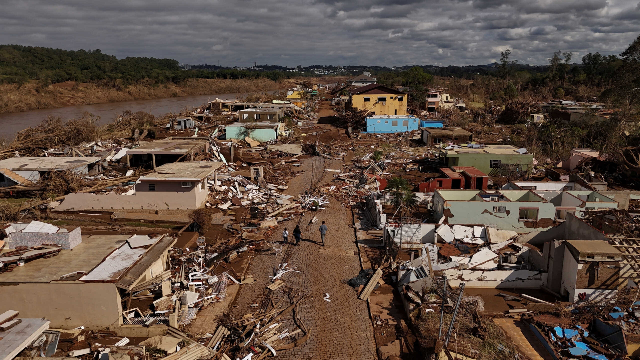 A drone view shows people walking on a street near damaged houses after the floods of the Taquari River in Arroio do Meio, Rio Grande do Sul state, Brazil, May 20, 2024. REUTERS
