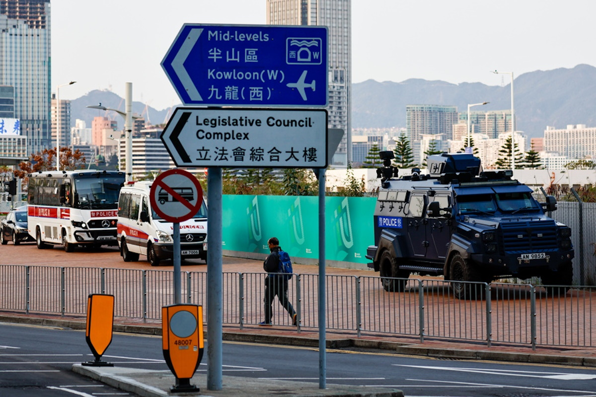 epa11229251 A man walks past a police armoured vehicle and police cars parked outside the legislative council, as the Article 23 is set to pass into the local law, in Hong Kong, China, 19 March 2024. Article 23, required by a Beijing-imposed National Security Law, has sparked international concerns about its impact on press freedom, religious freedom, and fundamental rights. Foreign governments such as the United Kingdom, the United States, Australia, and some European countries have also expressed concerns over the legislation.  EPA