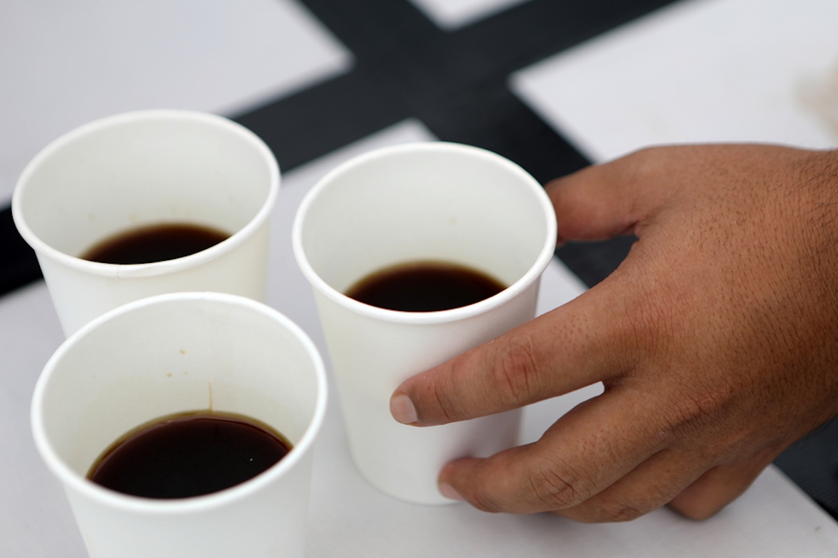 epa09845754 A man holds a coffee paper cup during the cupping competition at the Aceh Coffee Festival in Banda Aceh, Indonesia, 24 March 2021. Coffee is one of Aceh's main exports with its Gayo Arabica and Robusta varieties widely consumed around Europe.  EPA