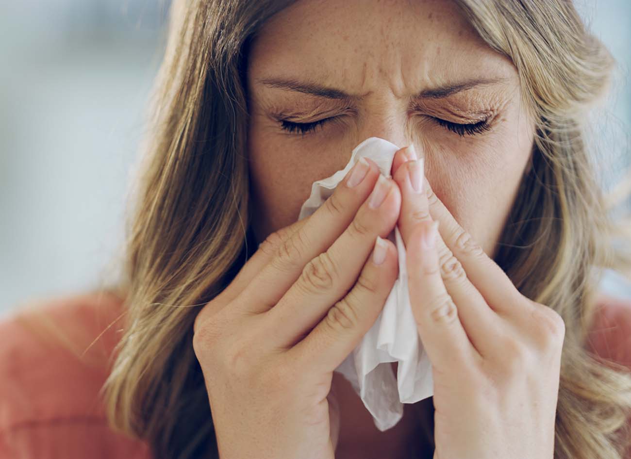 Shot of an attractive young woman feeling ill and blowing her nose with a tissue at home