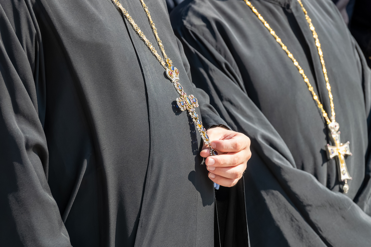 Orthodox priest holding cross hanging from neck.