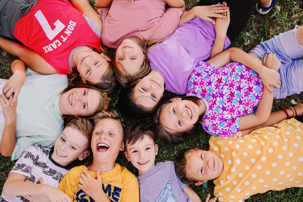 High angle view of a group of kids lying down while they laugh at the camera