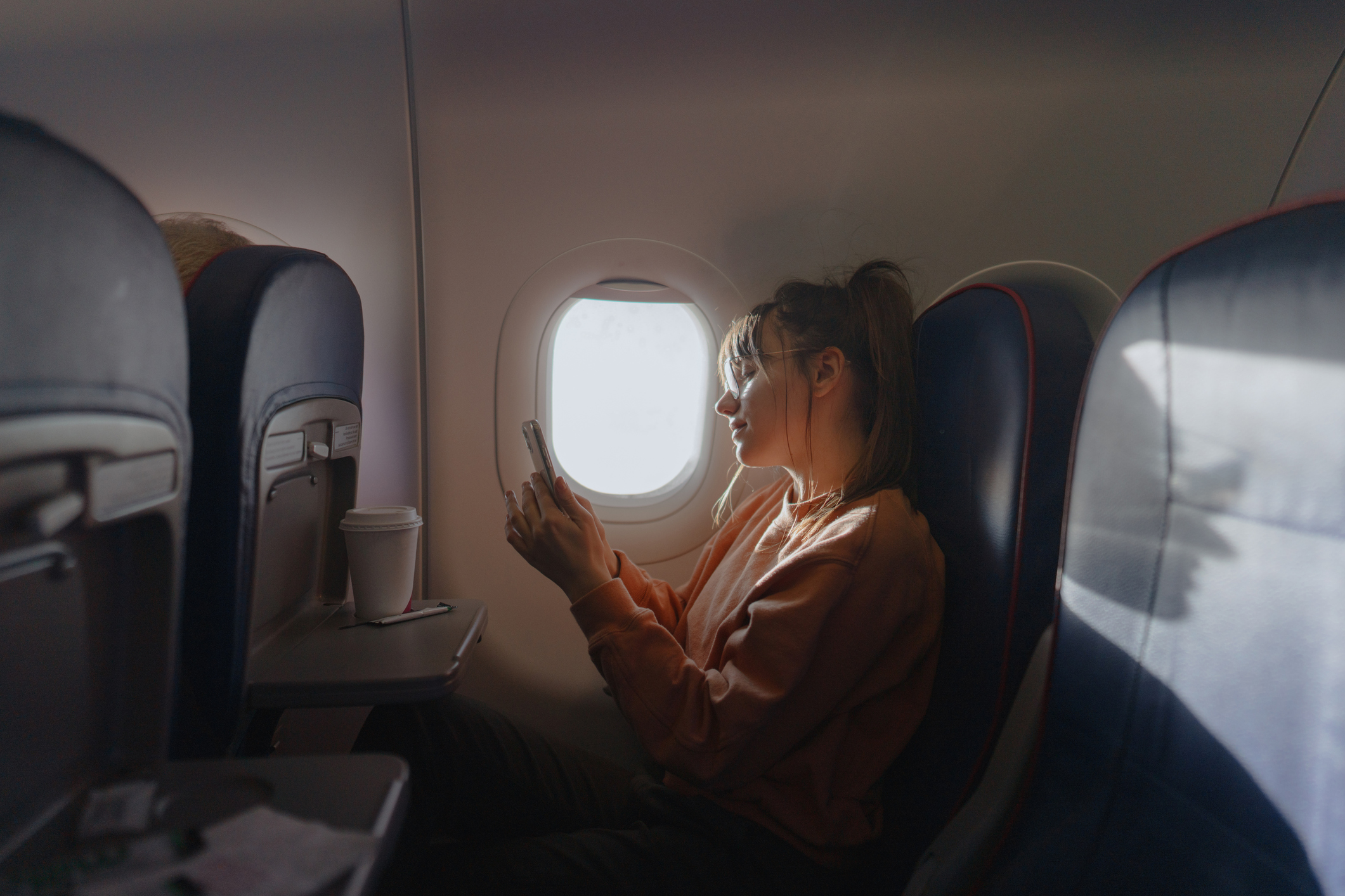 Photo of a young woman checking her smartphone during a flight.