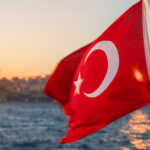 Waving Turkish flag on a ferry boat against Bosporus or Strait of Istanbul at sunset