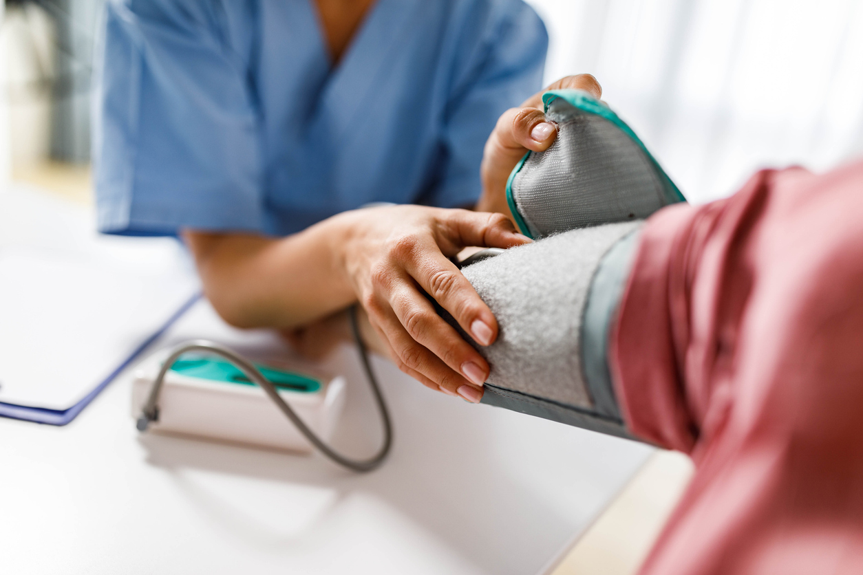 Close up of unrecognizable female nurse measuring blood pressure of a woman during her home visit.