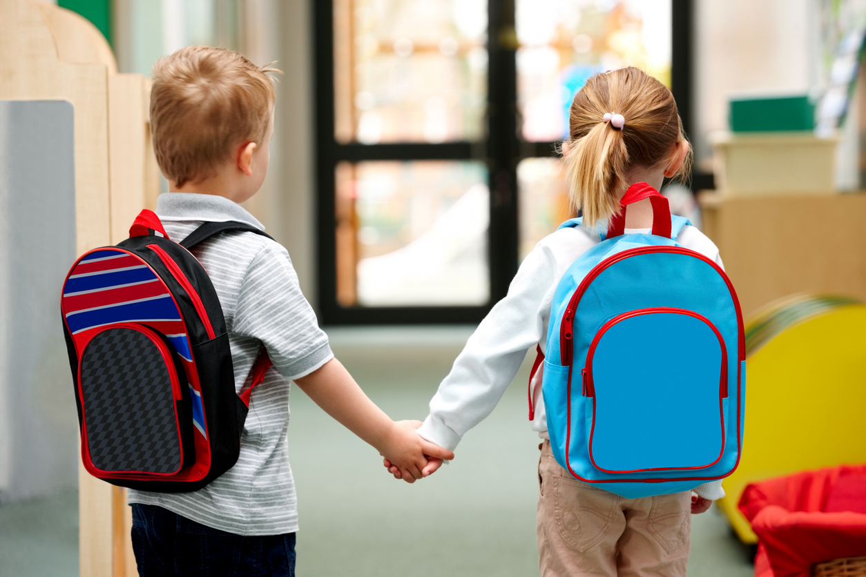 Two cute little children walking to school - Rear view