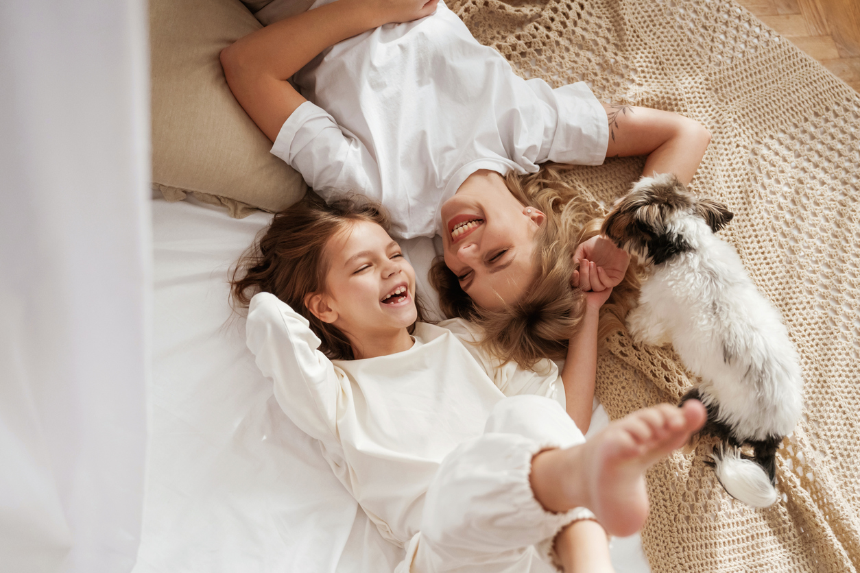 Cute dog is with them. Mother with daughter are at home together.