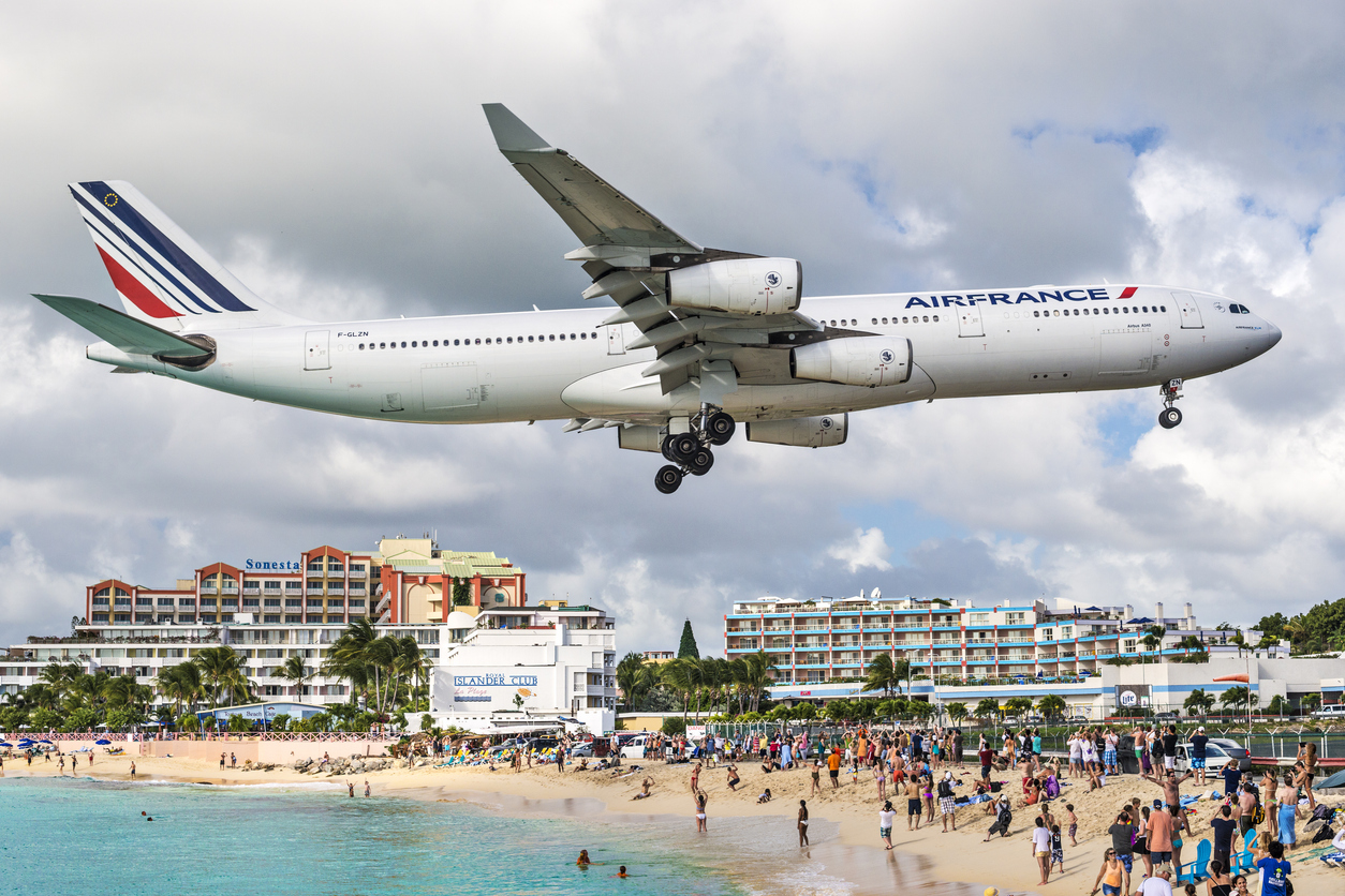 Philipsburg, Sint Maarten - December 30, 2013: A commercial jet approaches Princess Juliana airport above onlooking spectators. The short runway gives beach goers close proximity views of the planes.