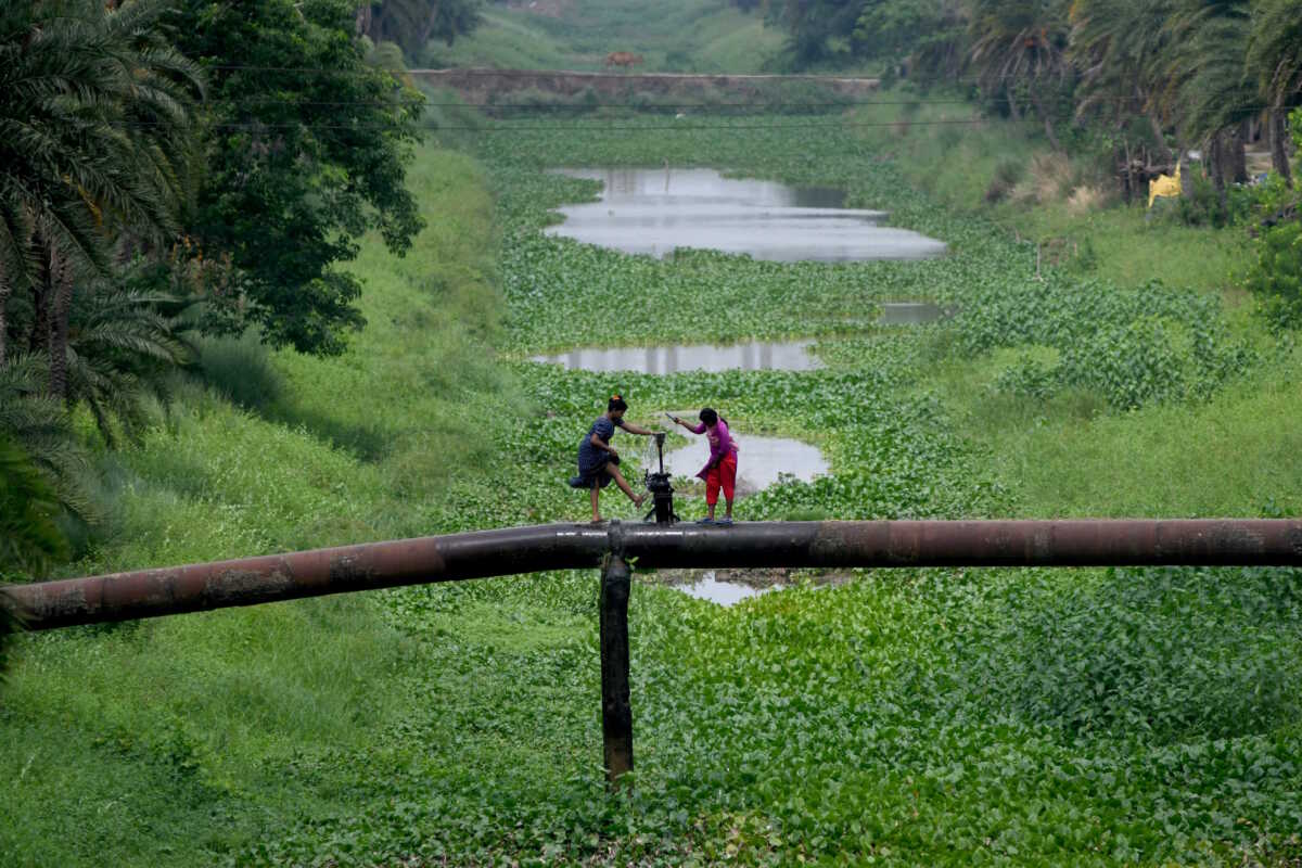 Women wash their feet from a leaked valve of a water pipe laid across a canal in Kendrapara district in the eastern state of Odisha, India, May 30, 2024. REUTERS