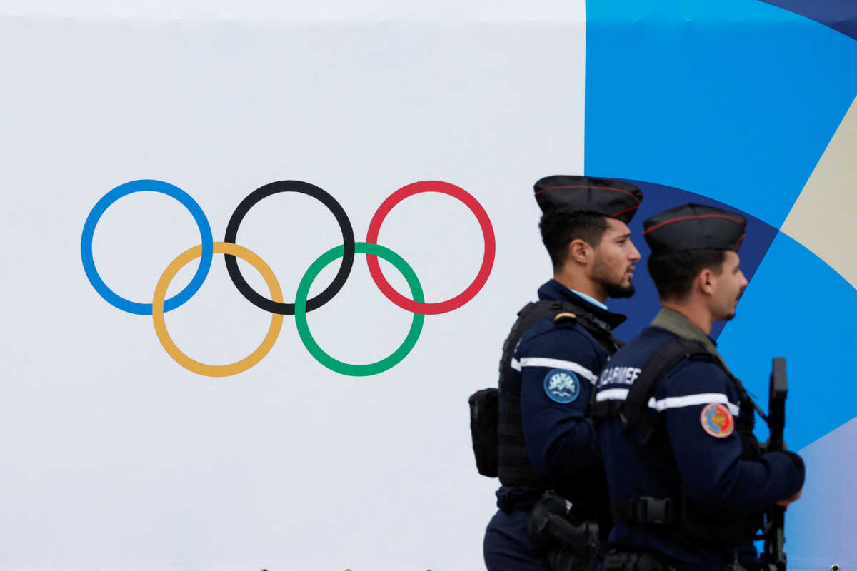 French gendarmes walk past the logo of the Paris 2024 Olympic and Paralympic Games in front of the National Assembly in Paris, France, May 2, 2024. REUTERS