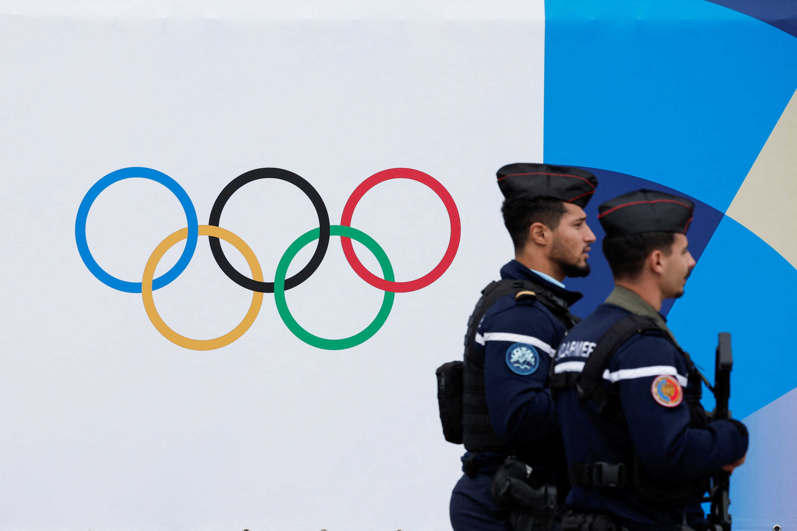 French gendarmes walk past the logo of the Paris 2024 Olympic and Paralympic Games in front of the National Assembly in Paris, France, May 2, 2024. REUTERS