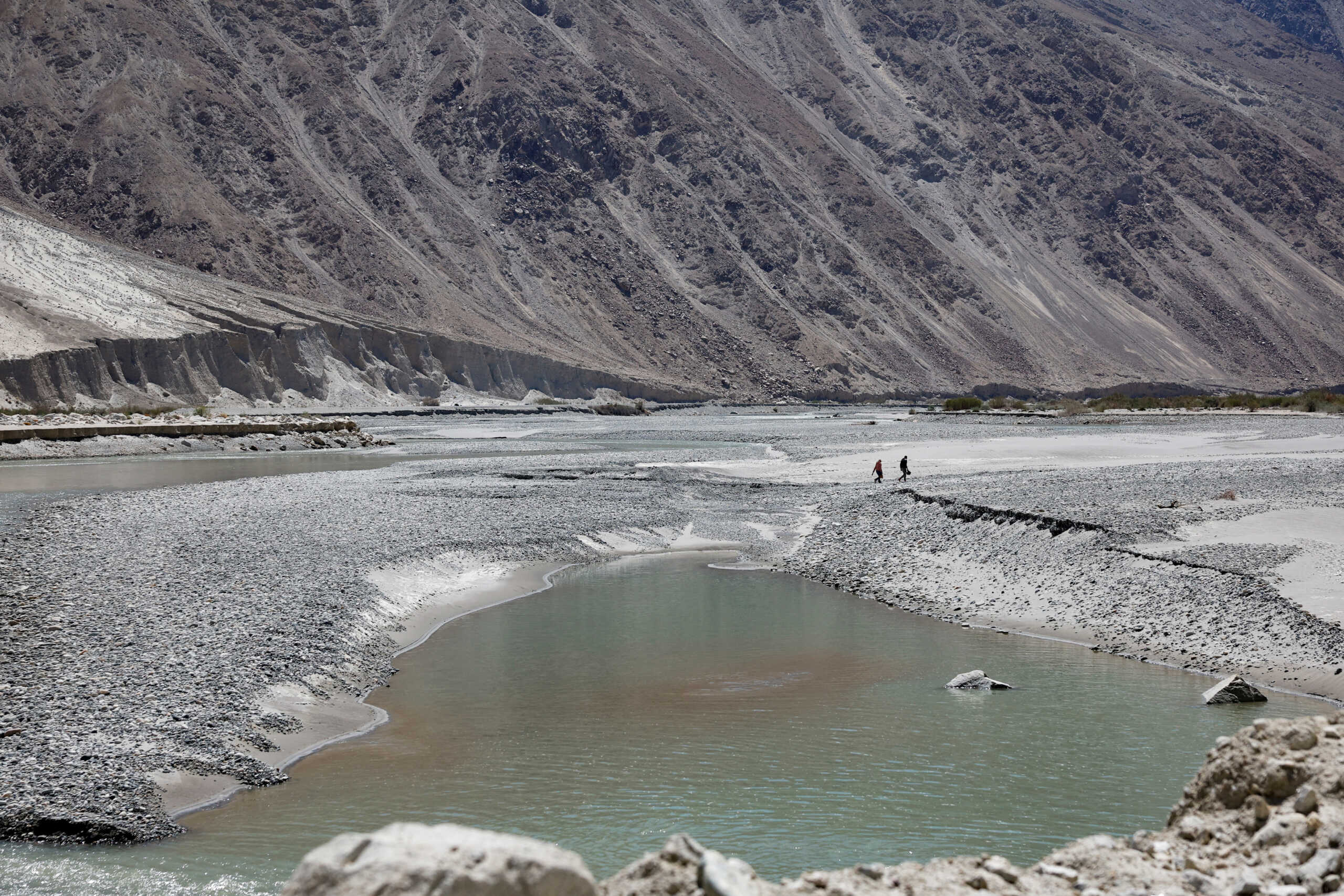 A biker couple walks near the Shyok River on a sunny day in the Ladakh region, India, May 21, 2024. REUTERS