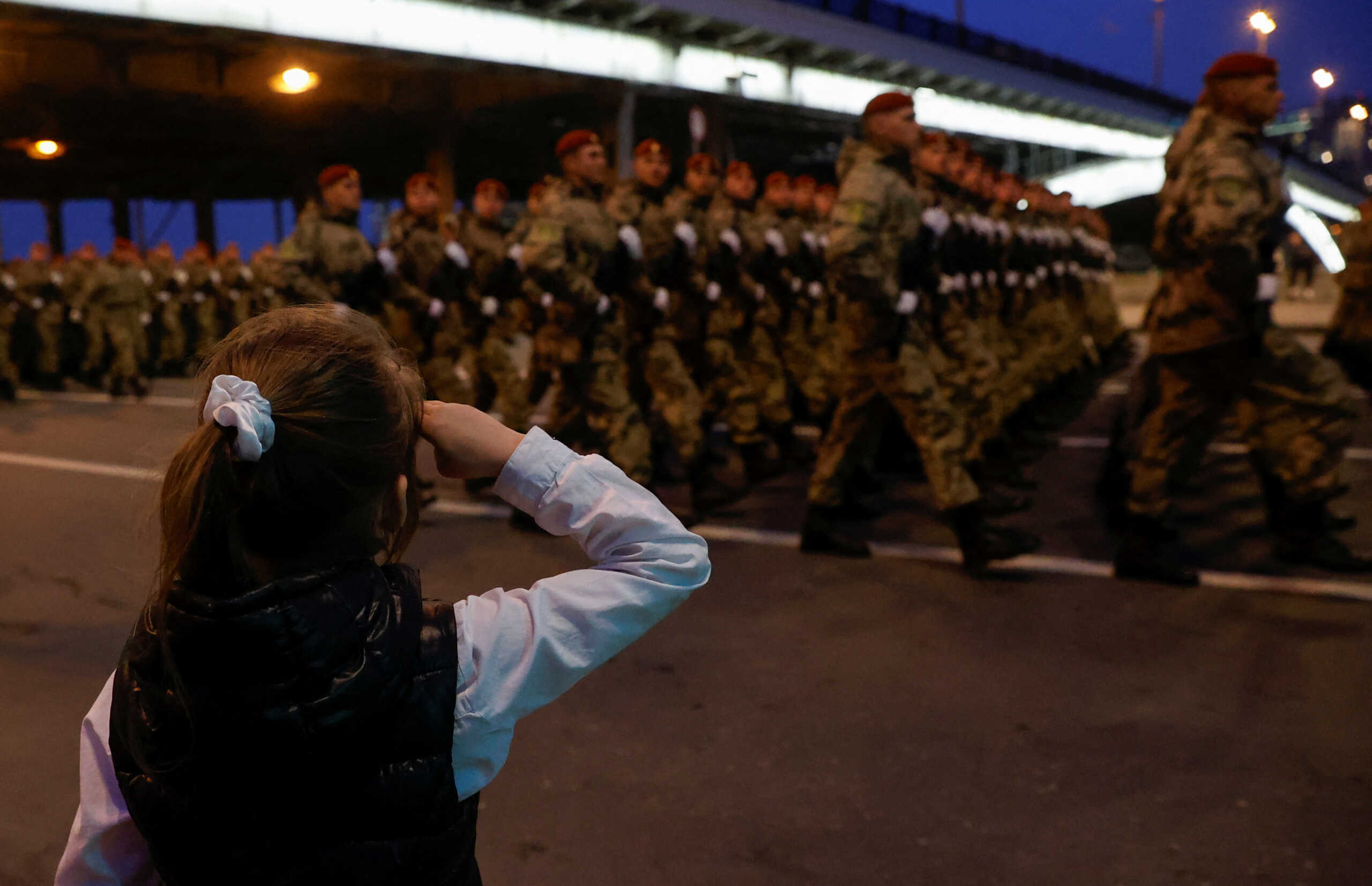 A child watches Russian service members marching in columns before a rehearsal for a military parade, which marks the anniversary of the victory over Nazi Germany in World War Two, in central Moscow, Russia, April 26, 2024. REUTERS