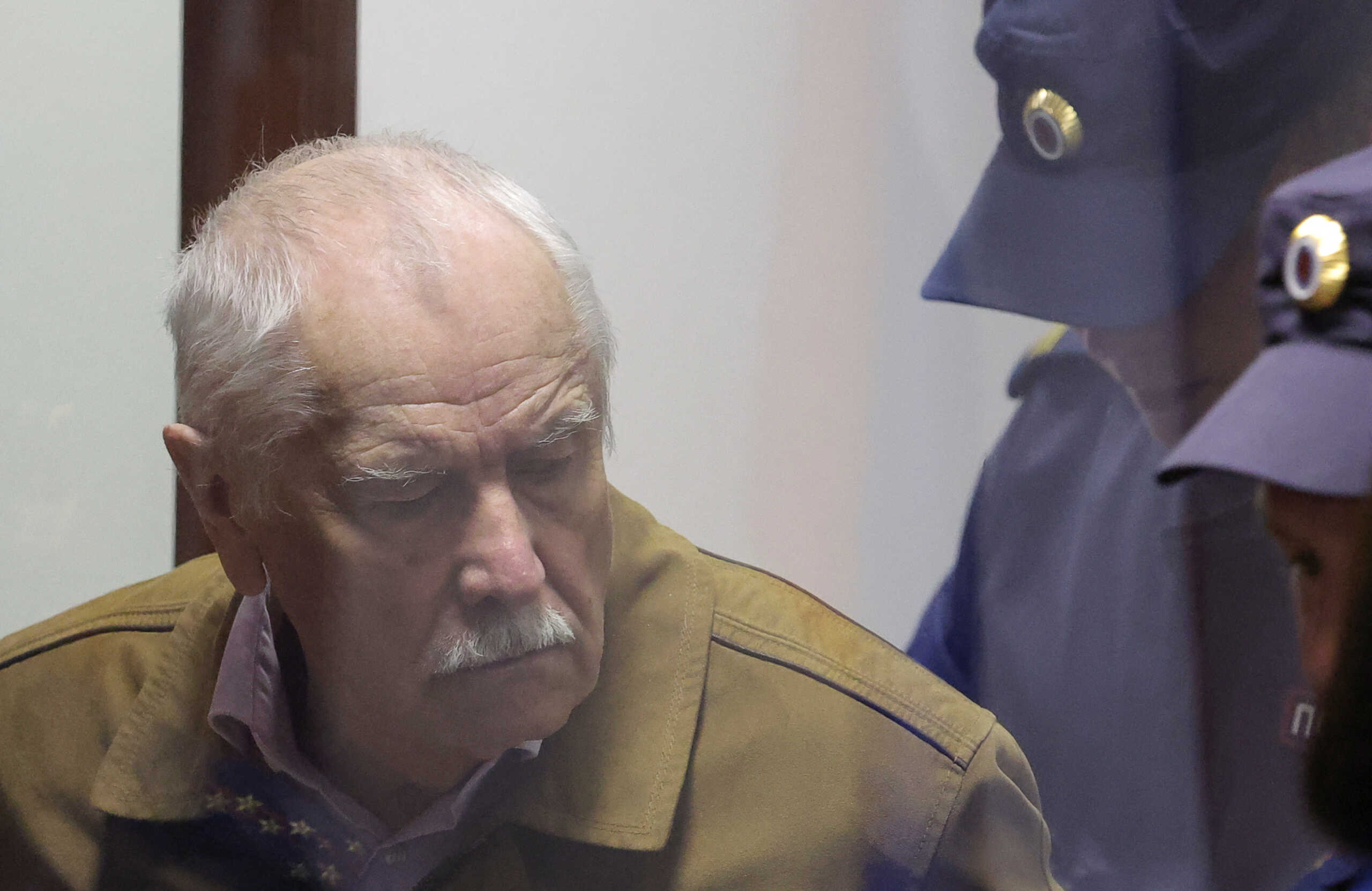Russian physicist Anatoly Maslov, who was arrested in 2022 and accused of state treason, stands behind a glass wall of an enclosure for defendants before a court hearing in Saint Petersburg, Russia, May 21, 2024. REUTERS