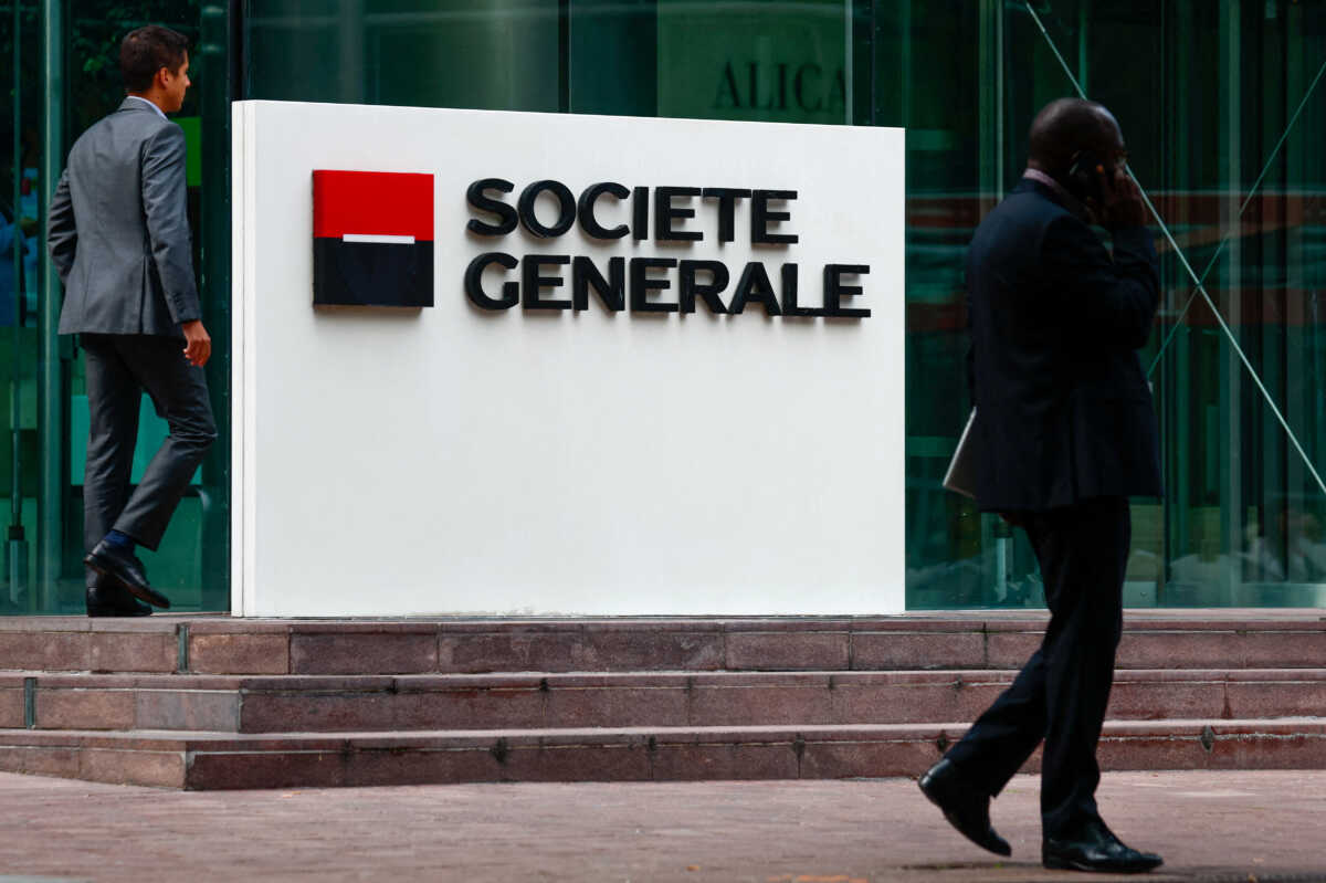 FILE PHOTO: People walk past a logo of French bank Societe Generale in front of the company's skyscraper at the financial and business district of La Defense near Paris, France September 14, 2023. REUTERS