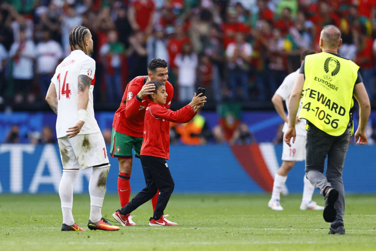 Soccer Football - Euro 2024 - Group F - Turkey v Portugal - Dortmund BVB Stadion, Dortmund, Germany - June 22, 2024 Young pitch invader takes a selfie with Portugal's Cristiano Ronaldo before being detained by stewards REUTERS