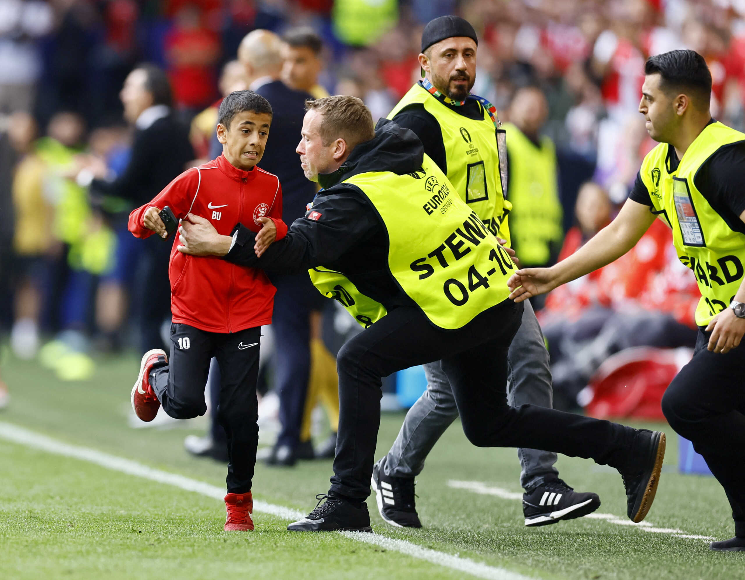 Soccer Football - Euro 2024 - Group F - Turkey v Portugal - Dortmund BVB Stadion, Dortmund, Germany - June 22, 2024 Young pitch invader is detained by stewards during the match REUTERS