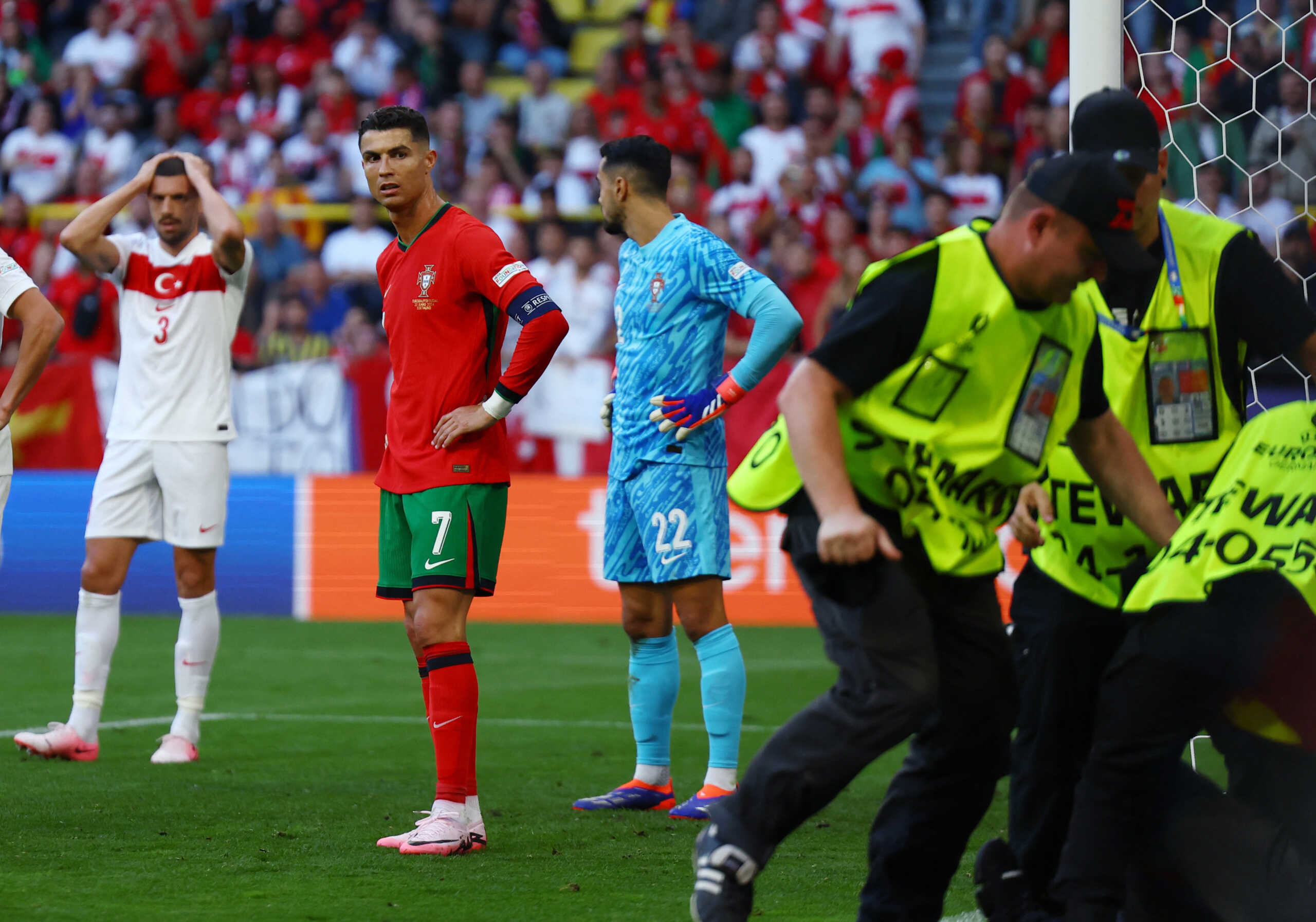 Soccer Football - Euro 2024 - Group F - Turkey v Portugal - Dortmund BVB Stadion, Dortmund, Germany - June 22, 2024 Pitch invader is detained by stewards as Portugal's Cristiano Ronaldo looks on REUTERS