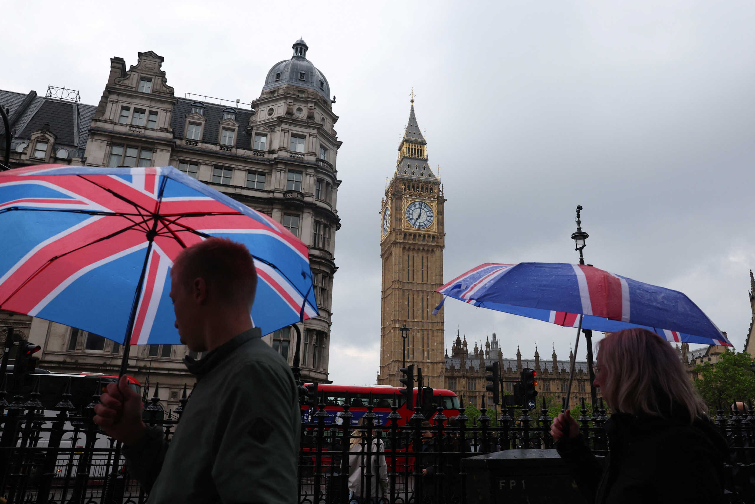 People, shielding themselves with Union flag umbrellas, walk near the Elizabeth Tower, more commonly known as Big Ben, on the day British Prime Minister Rishi Sunak called for a general election, in London, Britain, May 22, 2024. REUTERS
