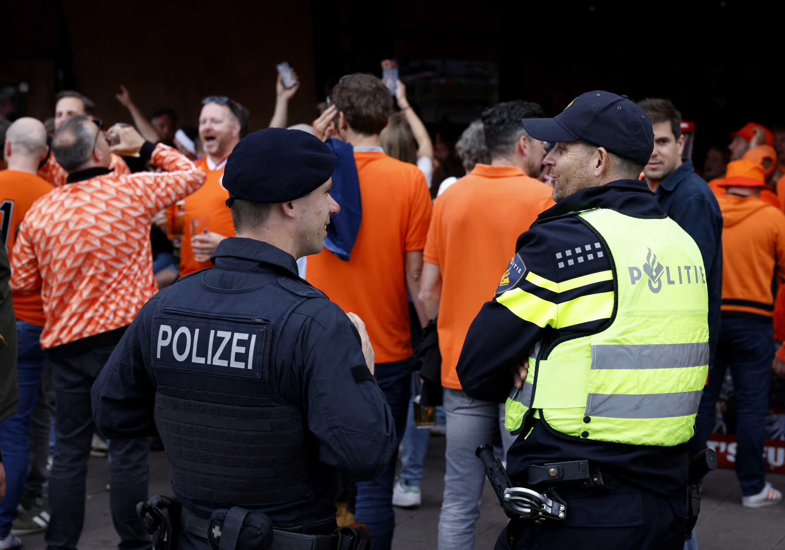 Soccer Football - Euro 2024 - Fans before Poland v Netherlands - Hamburg, Germany - June 15, 2024 Netherlands fans gather before Poland v Netherlands as police officers look on REUTERS