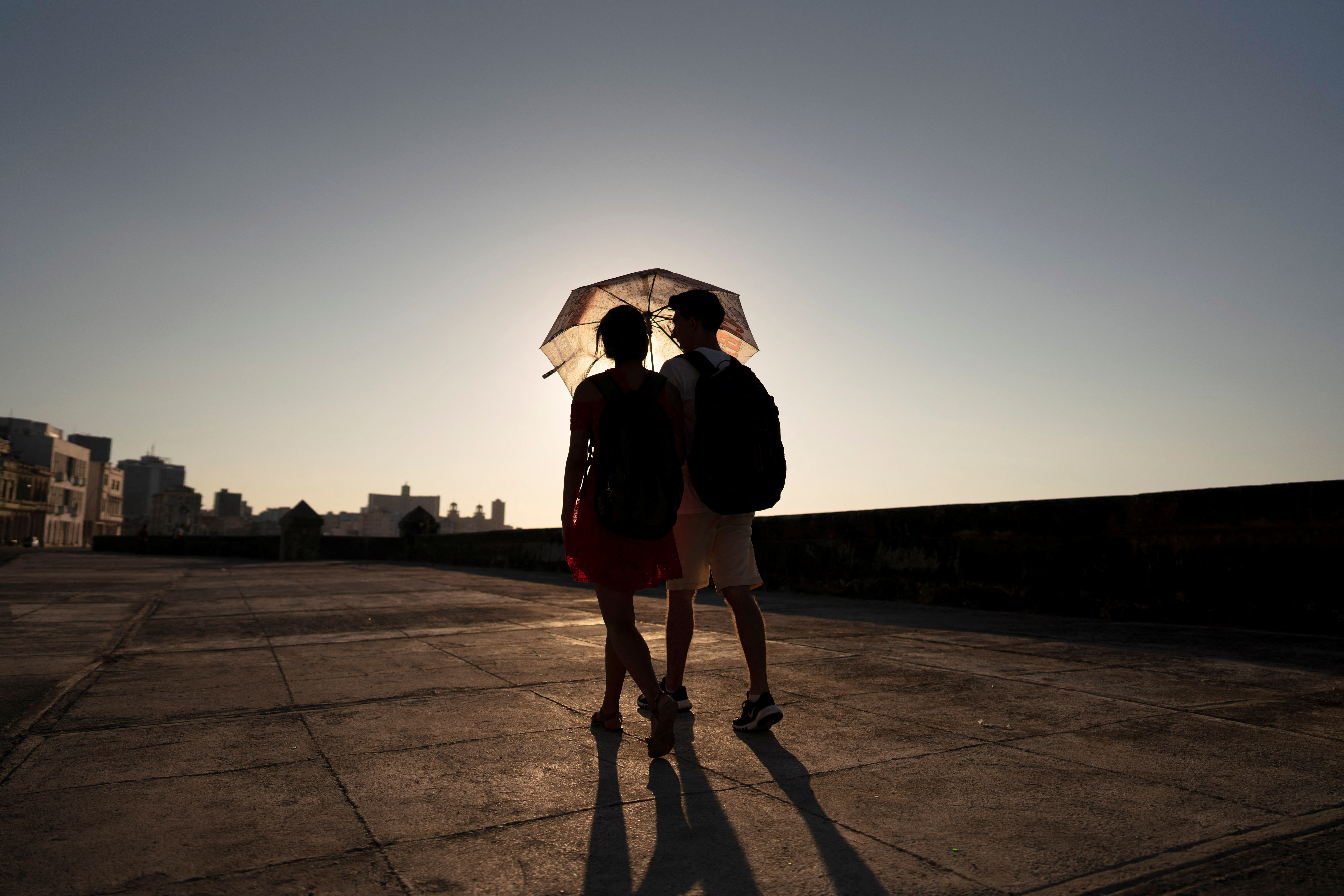 A couple protects themselves against the sun as they walk on the seafront of Malecon in Havana, Cuba, May 24, 2024. REUTERS