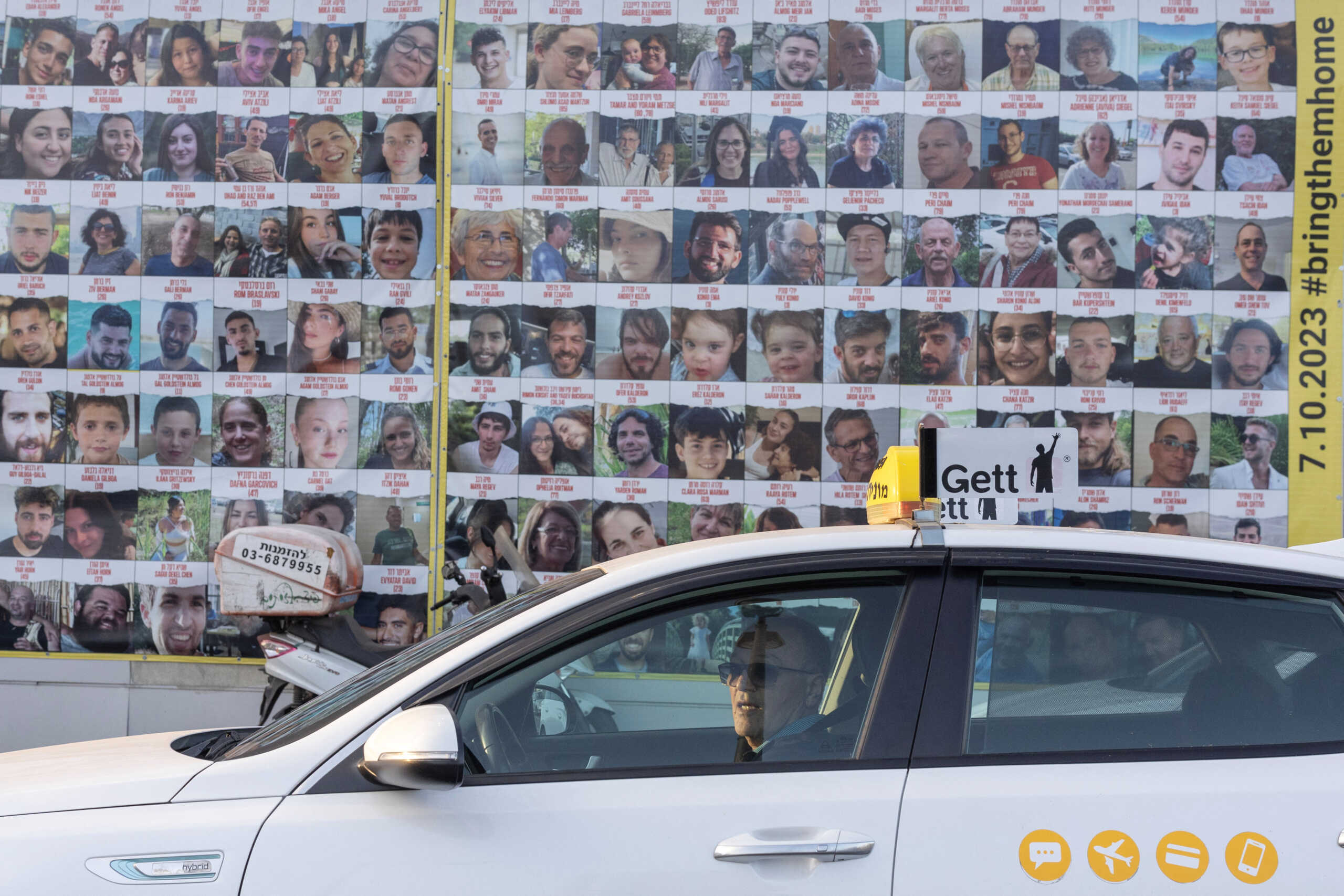A man drives a taxi past pictures of hostages kidnapped during the deadly October 7 attack by Hamas, in Tel Aviv, Israel June 9, 2024. REUTERS