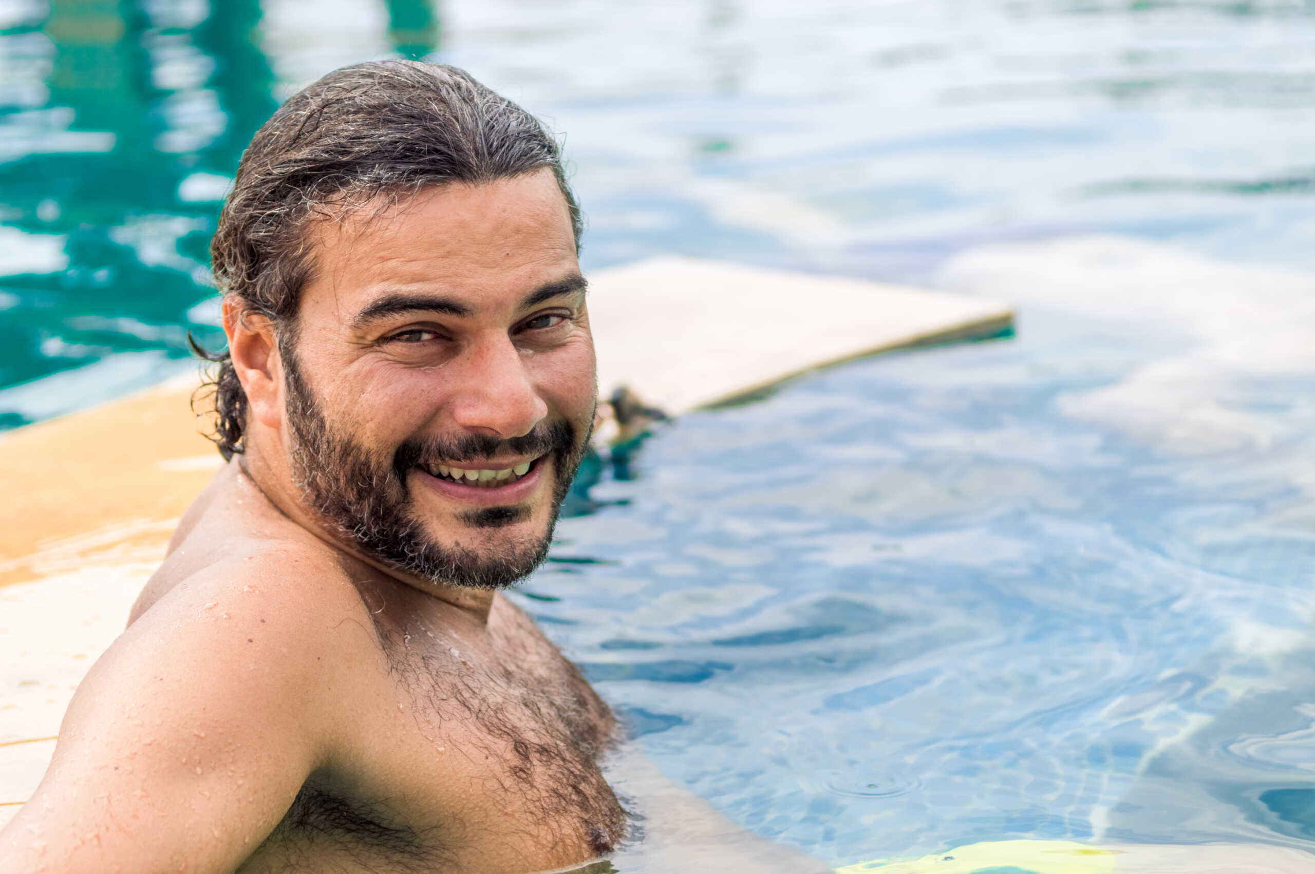 Happy bearded man relaxing in the swimming pool in a resort