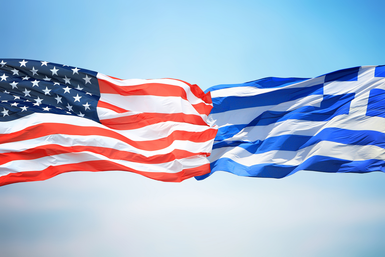 Flags of the USA and Greece against the background of the blue sky
