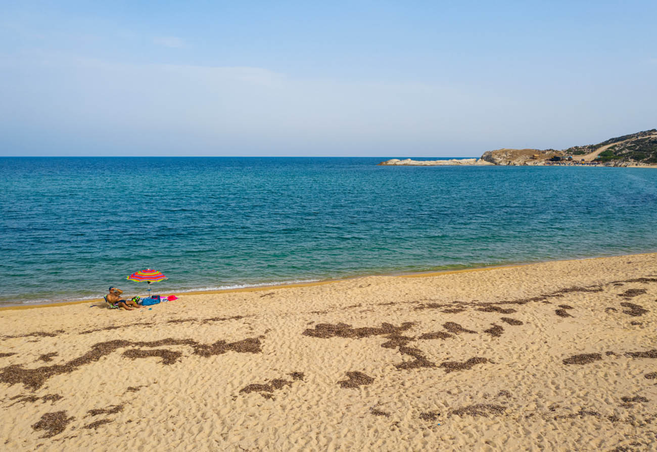 Sithonia, Greece - September 13, 2021: Man lies on sun chair on the beach with colourful sun umbrella