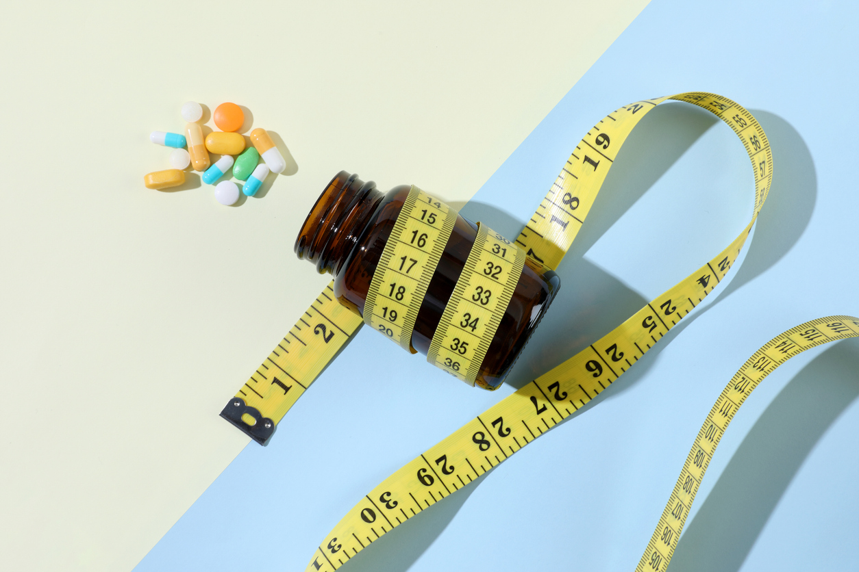 Diet pills and bottle of diet supplements with measuring tape