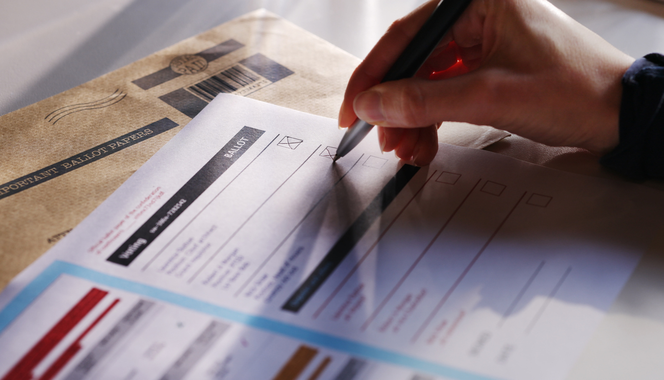 Stock image showing a woman’s hand filling in a postal ballot