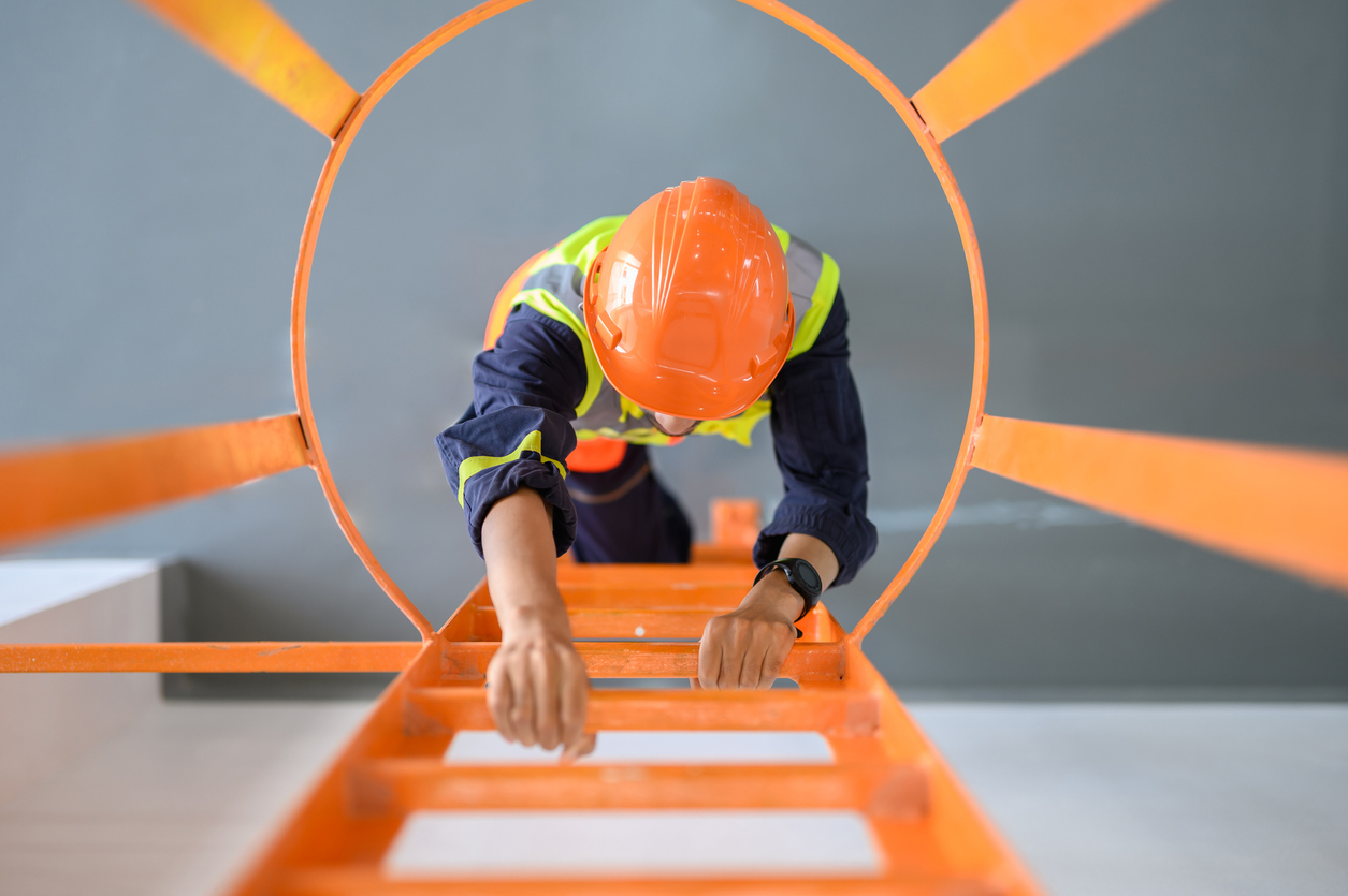 High angle look down view over young Asian technician worker climbing ladder for inspect or maintenance machine in high voltage electric transformer sub station. Industrial business occupation worker concept.